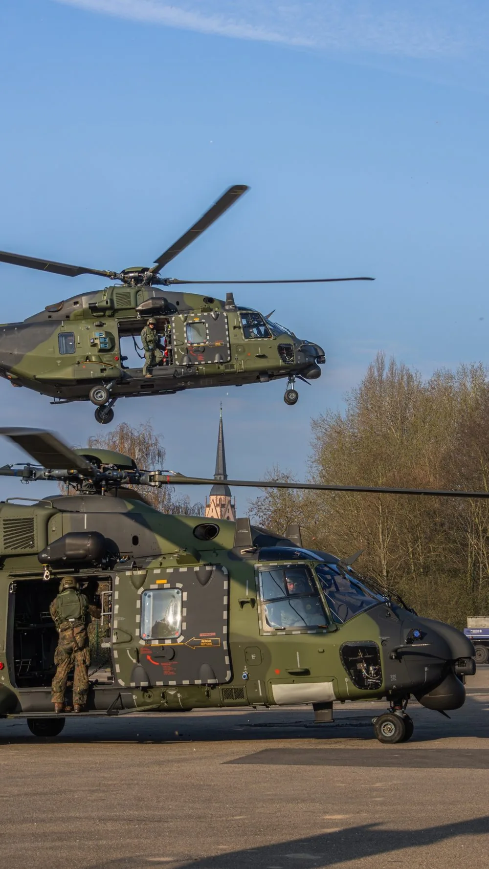 Zwei NH90-Hubschrauber der Bundeswehr bei einer Katastrophenschutzübung: einer im Schwebeflug, einer am Boden mit Soldaten